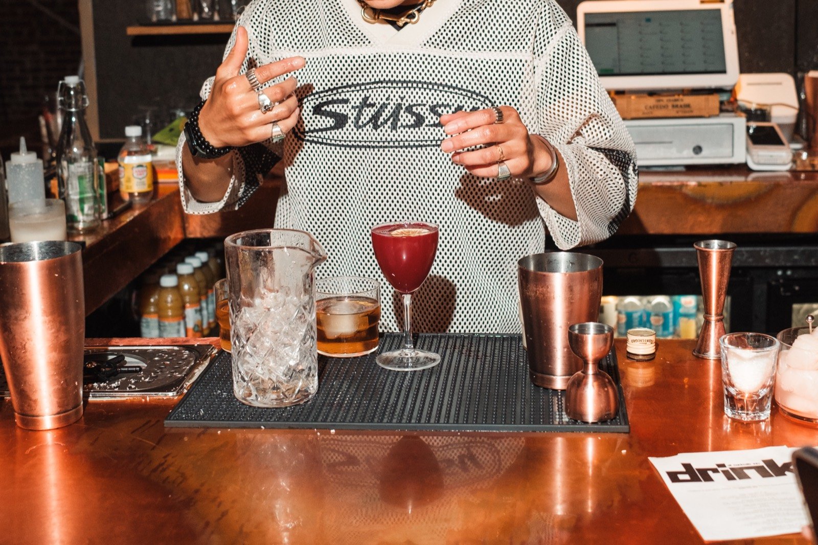 A cocktail beside a mixing glass on the bar